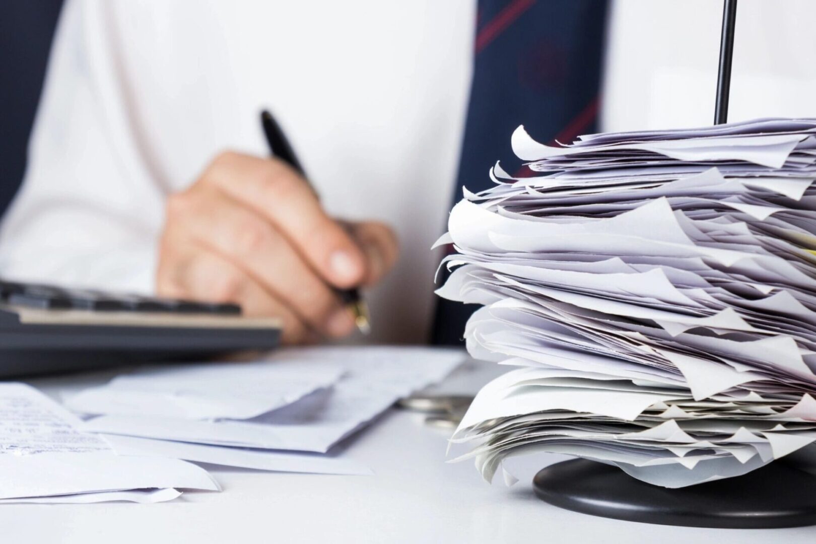 Stack of bills in paper nail with businessman calculating