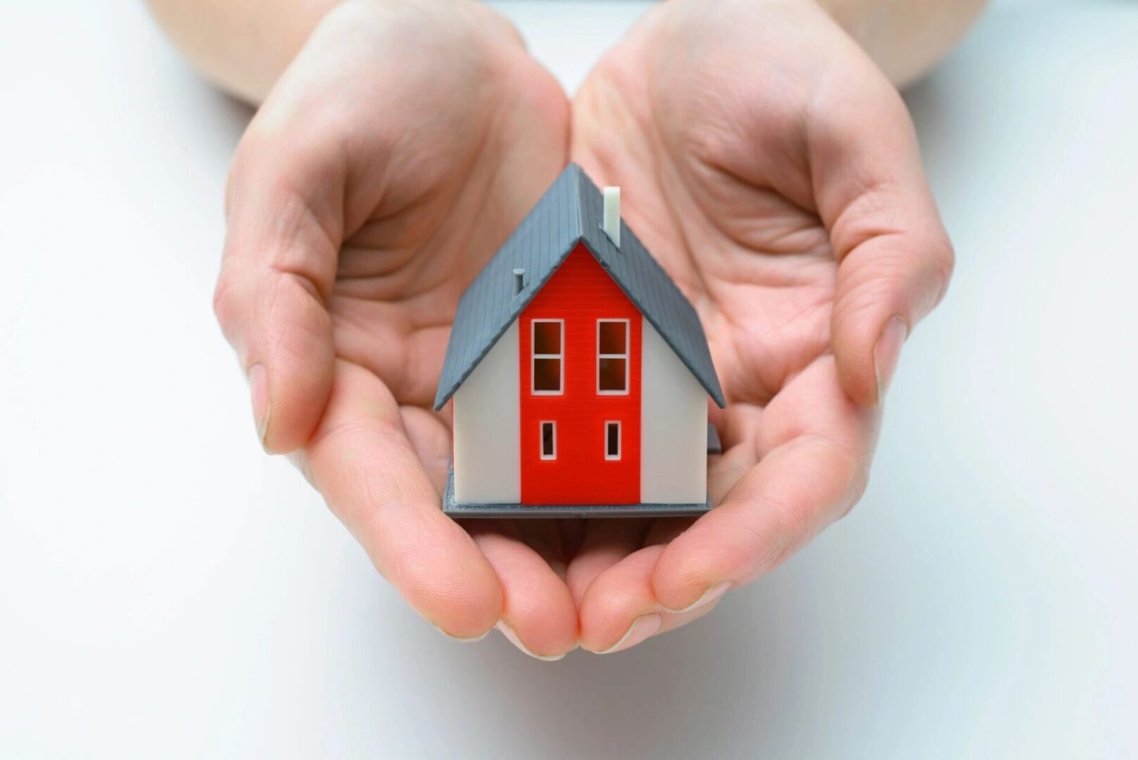 Hands presenting a small model of house