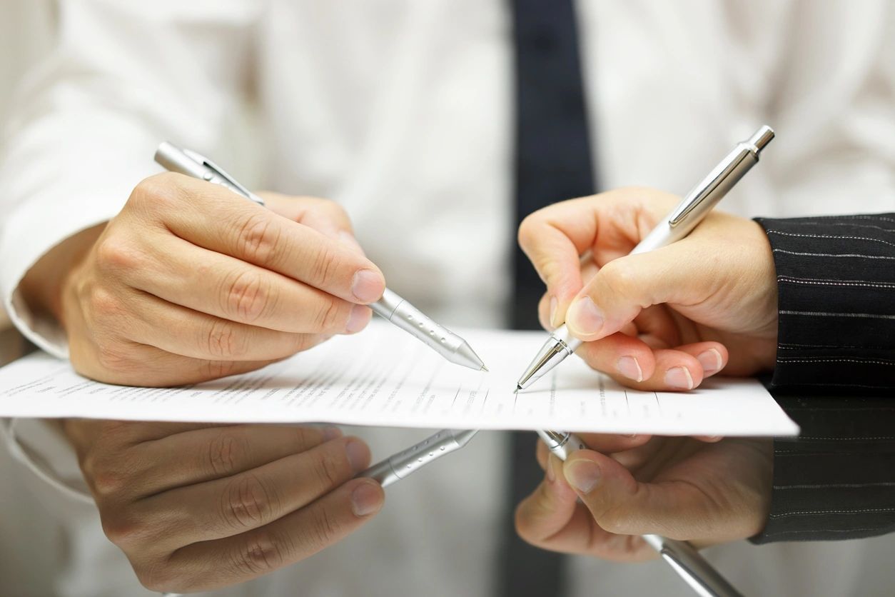 Business man is pointing woman where to sign document