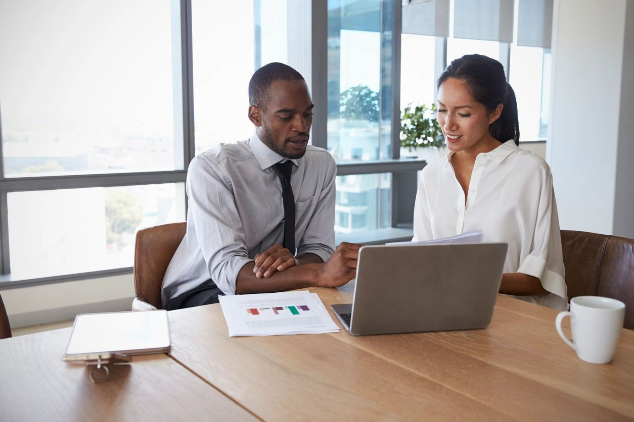 Businesspeople Working On Laptop In Boardroom Together